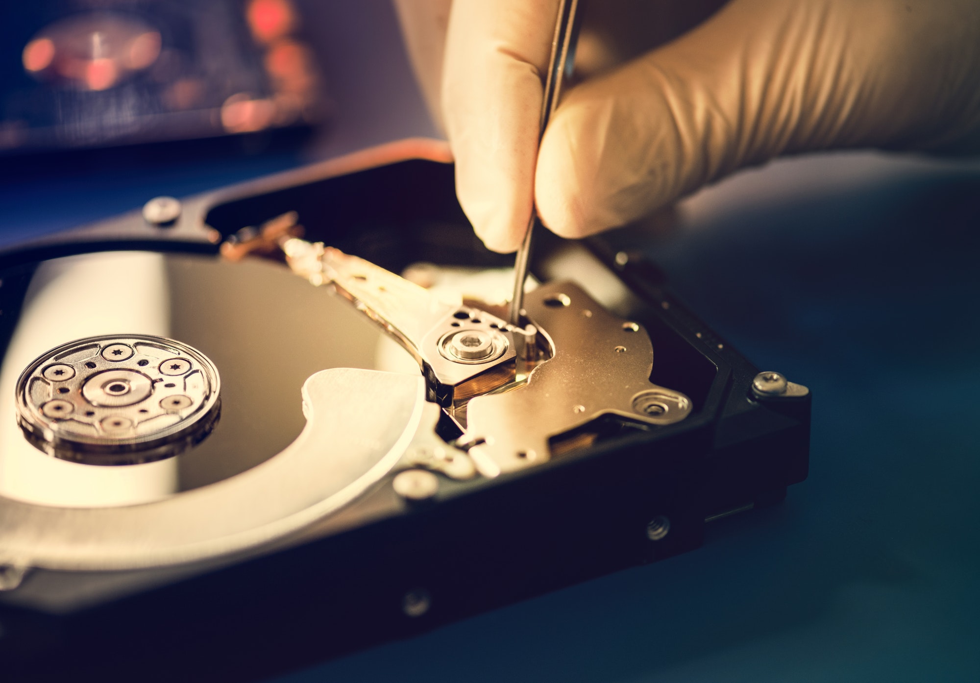 Closeup of hands with tweezers and computer hard disk